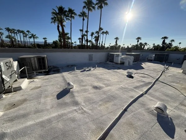 Completed commercial foam roof coating surrounding rooftop HVAC equipment.