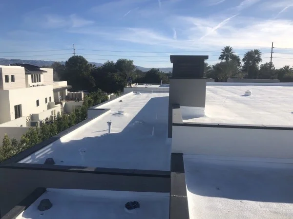 Finished white foam roof coating on modern flat roof.