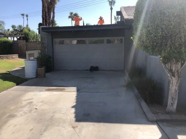 Roofing crew replacing residential roof above attached garage.