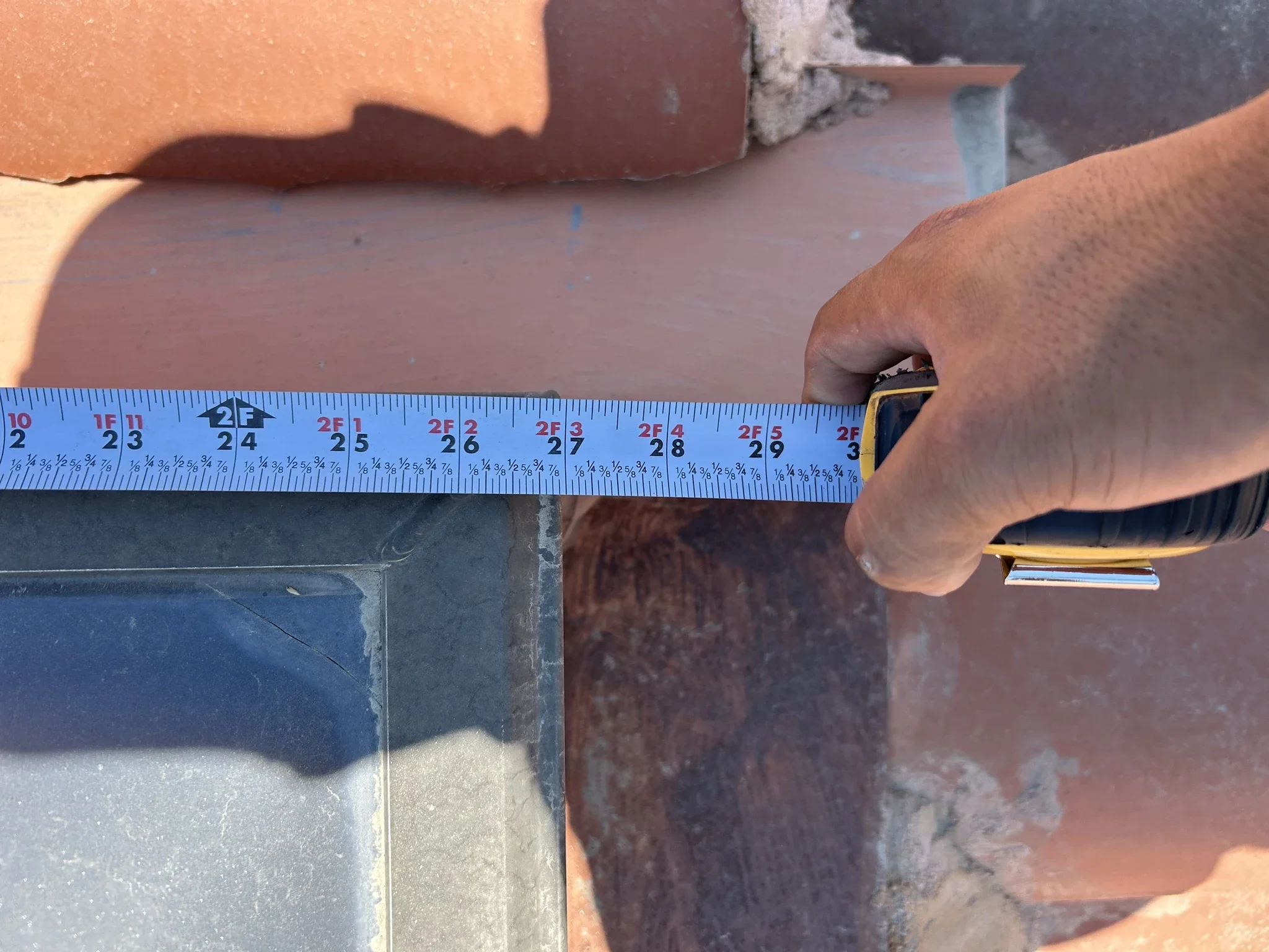 Roofer measuring a section of a residential tile roof