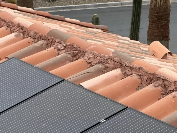 Roof valley mortar deterioration beside residential solar panel installation.