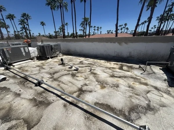 Weathered commercial flat roof showing widespread moisture staining