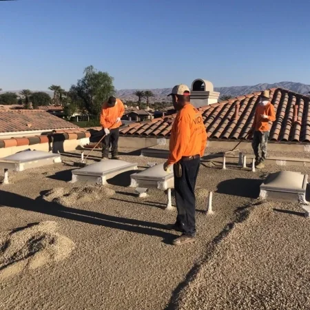 Roofing crew installing gravel on commercial flat roofing system.