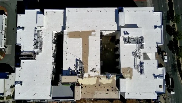 Aerial view of completed commercial white flat roofing system.