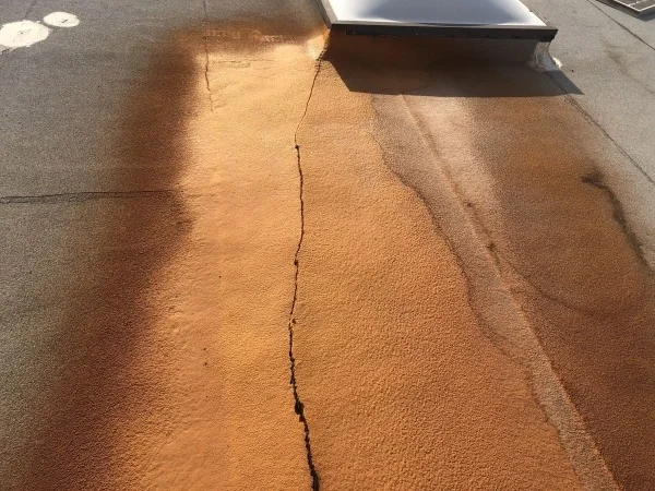 Cracked commercial roof coating requiring professional repair and restoration.