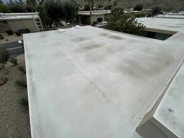 Existing white flat roof before recoating with visible weathering.