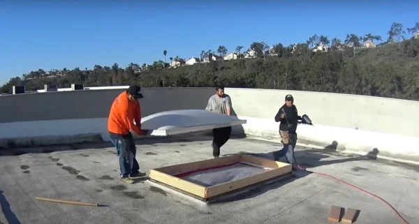 Roofers replacing skylight during commercial flat roof repair