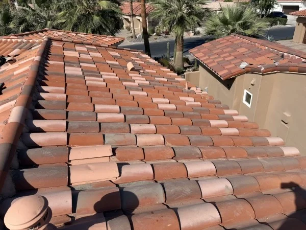 Completed concrete tile roof with uniform ridge and field tiles.