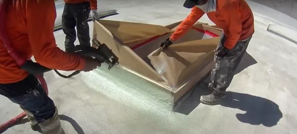 Crew masking skylight before applying spray foam roof coating