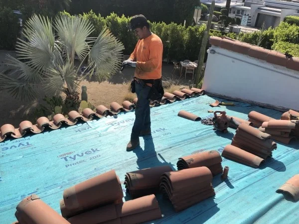 Roofer replacing clay tiles over protective roof underlayment