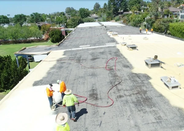Roofing crew restoring large commercial flat roof surface