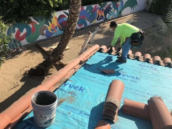 Roofer installing clay tiles over protective roof underlayment