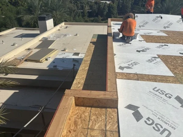 Roofer installing underlayment over exposed residential roof decking