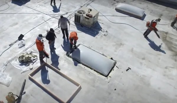 Roofing crew repairing skylight on commercial flat roof