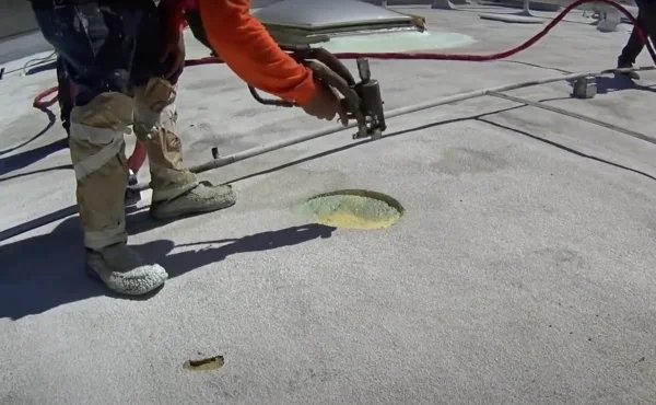 Roofer applying spray foam around damaged flat roof