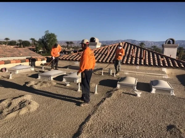 Roofers applying coating around residential flat roof skylights