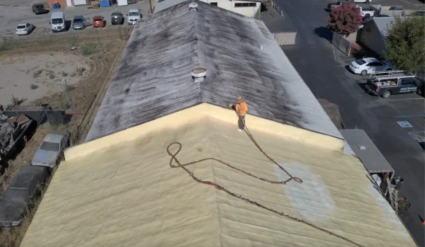 Roofer applying spray foam coating to commercial roof