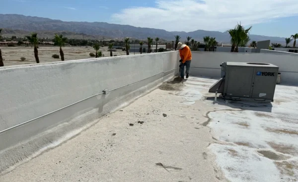 Roofer repairing commercial flat roof beside HVAC unit
