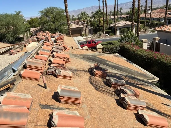 Damaged roof section with removed tiles awaiting structural repairs.