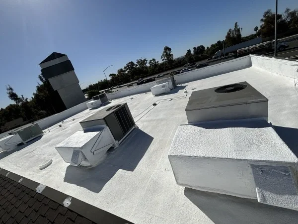 White coated commercial roof surrounding HVAC and vents