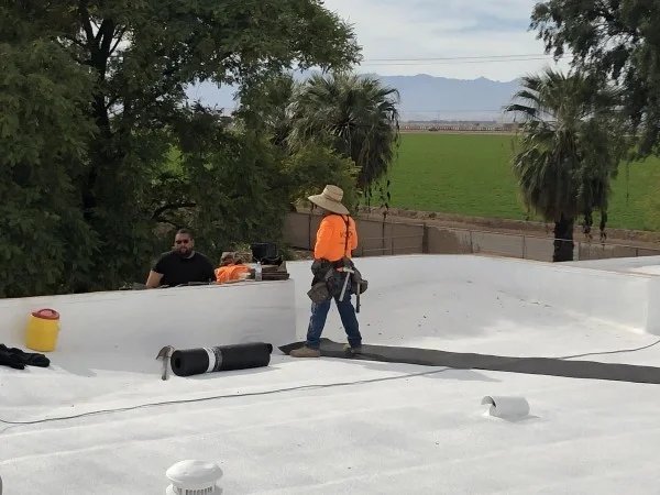 Roofer installing membrane material across residential flat roof