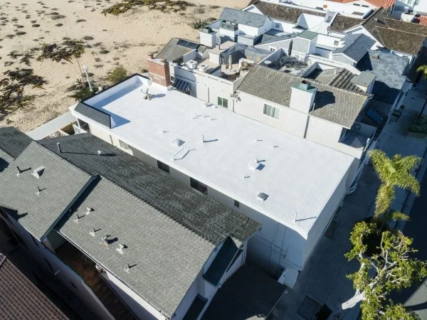 Aerial view of completed white flat roof installation