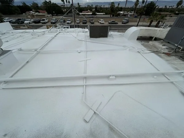 Fresh white foam roof coating covering rooftop mechanical piping.