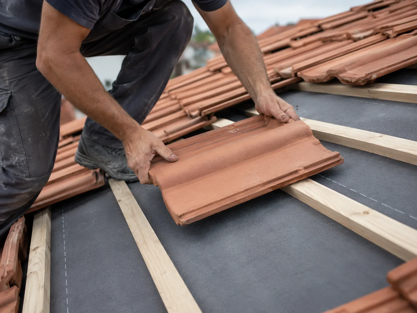 Roofer installing concrete tile with new underlayment on an Irvine re-roof