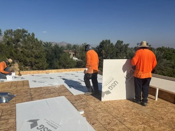 Crew installing rigid roof insulation boards on flat roof