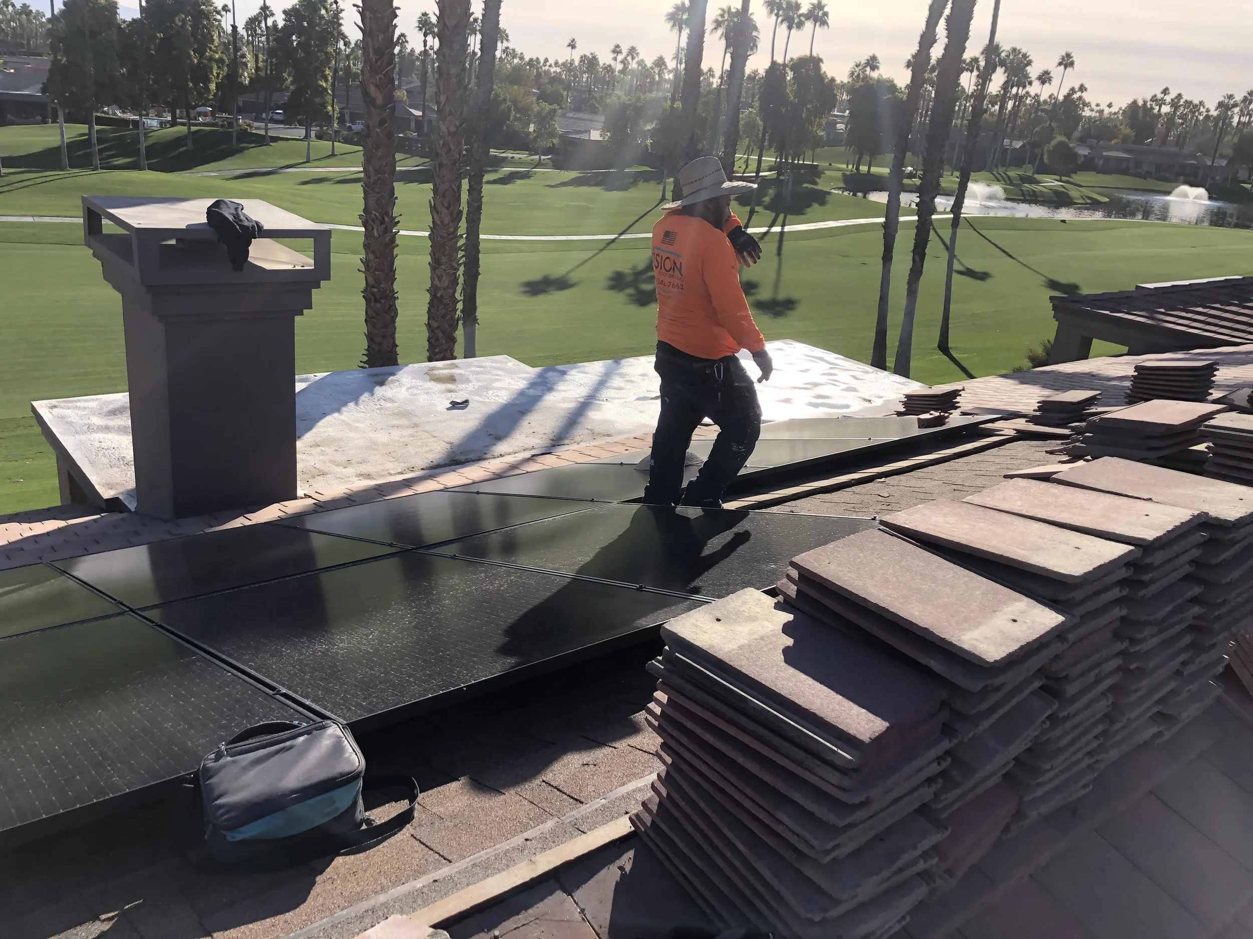 Roofer working beside solar panels and stacked roof tiles