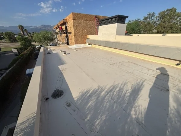 Modern flat roof nearing completion beside home construction project