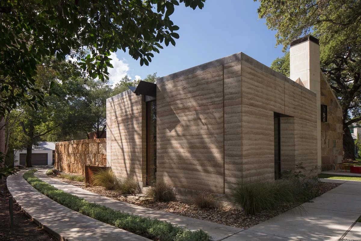 Rammed earth studio, driveway at left and approach to main entry at the right
