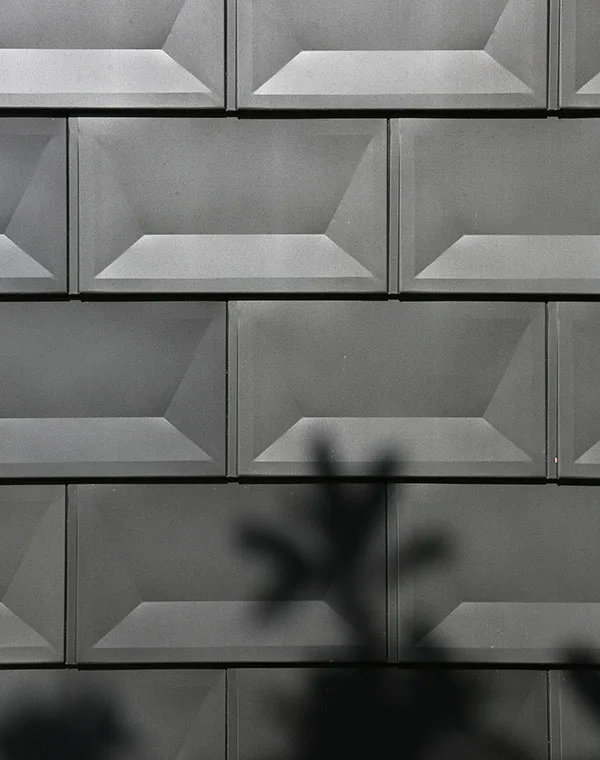 Shadow/light detail at sculpted aluminum wall tile