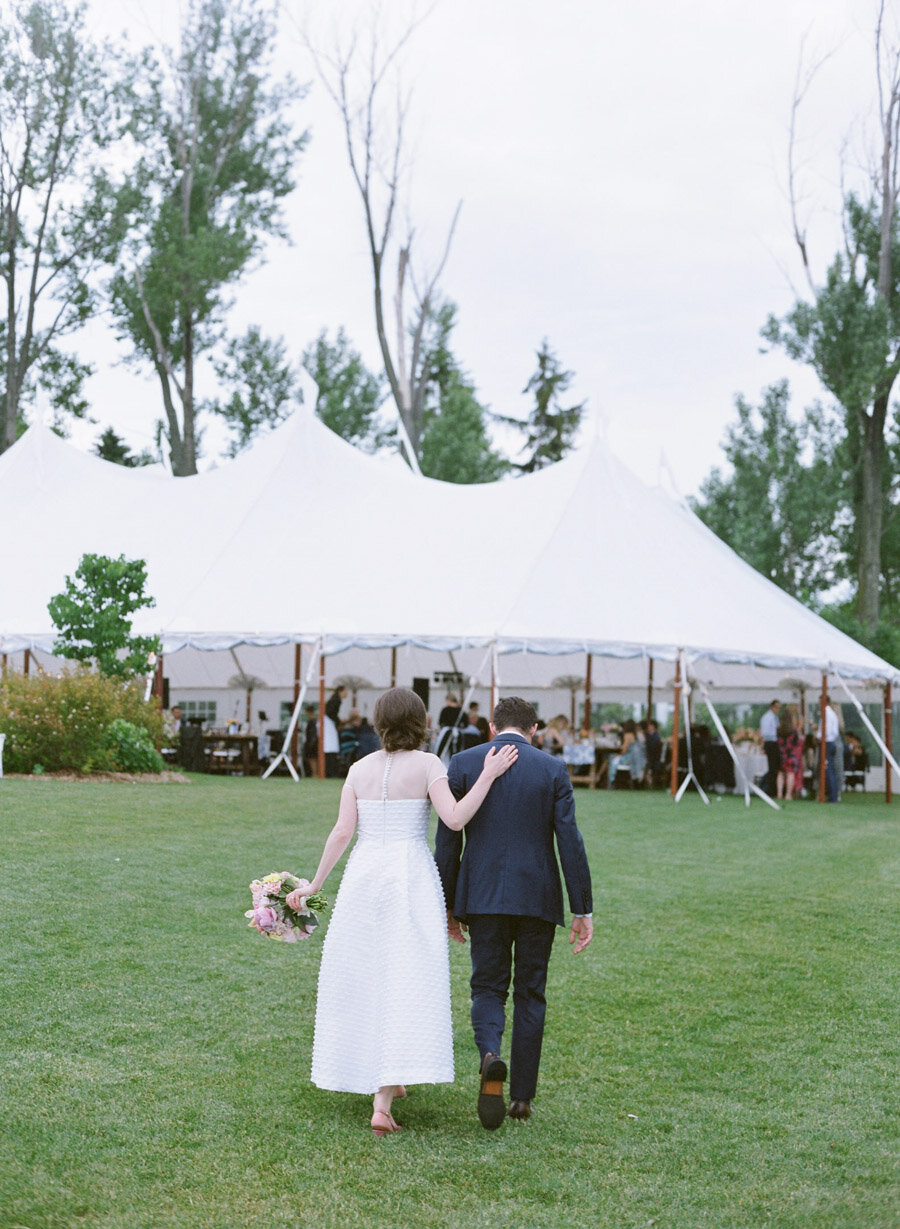 Bride and Groom walking bak to their tented reception in Door County