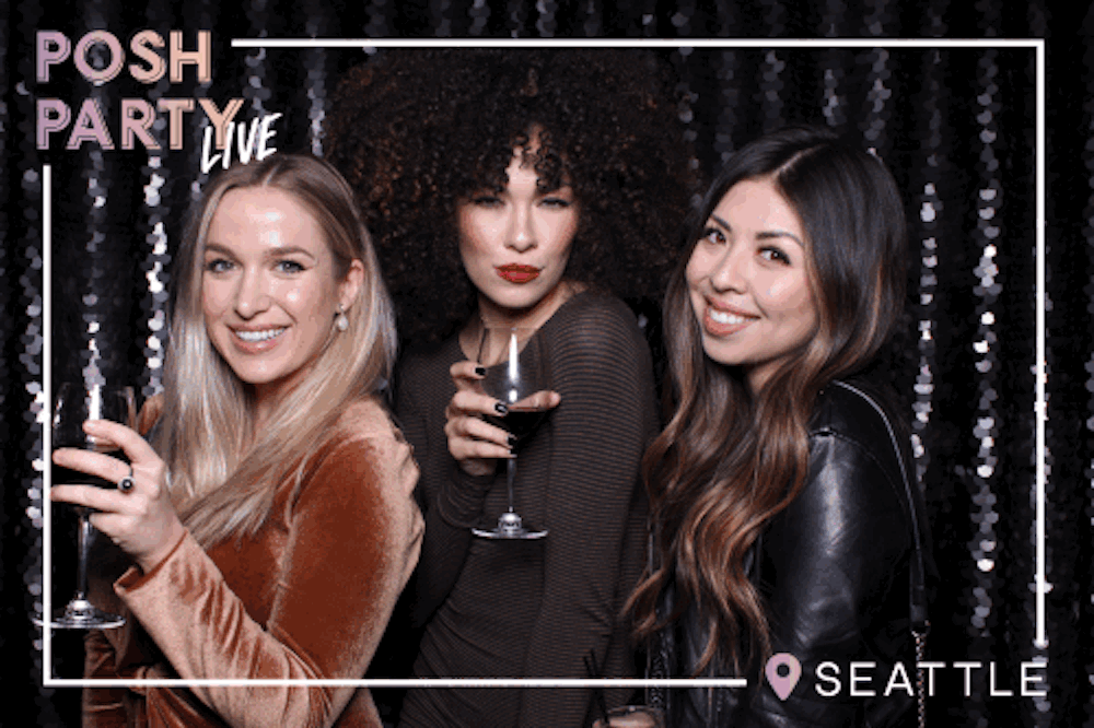 Three women at a Posh Party live event in Seattle, posing for a photo with drinks in front of a black and silver sequin backdrop.