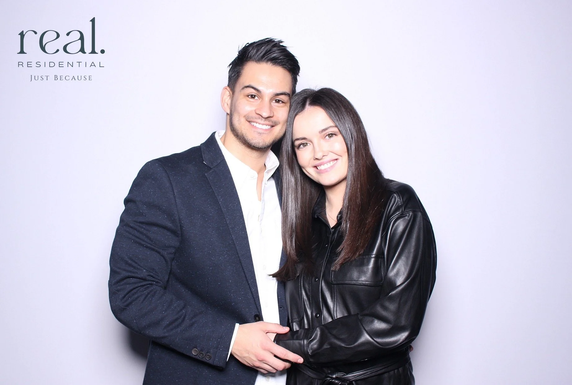 A smiling man and woman standing close together against a plain background, with the text 'real. RESIDENTIAL JUST BECAUSE' in the top left corner.