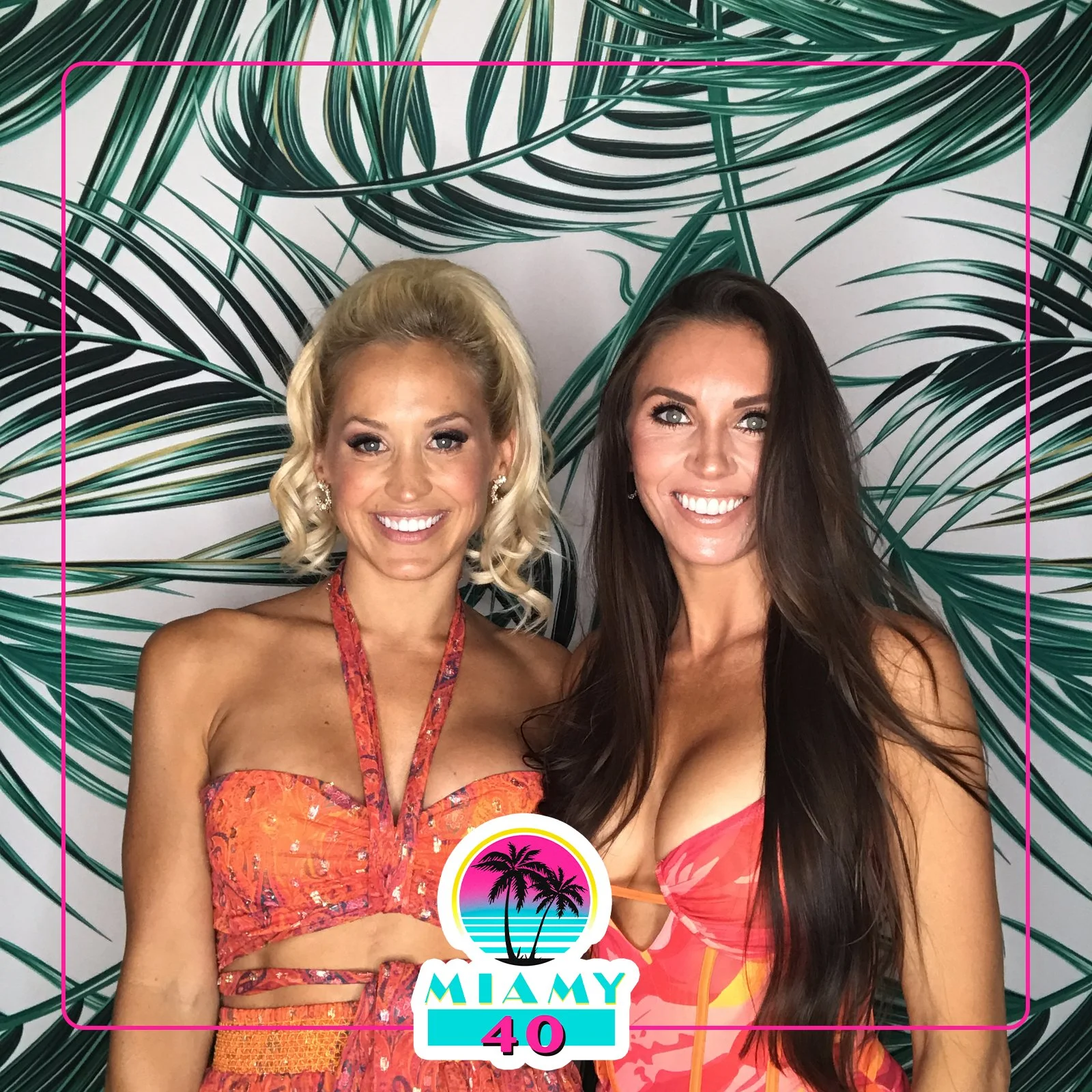 Two women in colorful summer dresses pose in front of a backdrop with green palm leaves, with a Miami 40th birthday logo at the bottom.