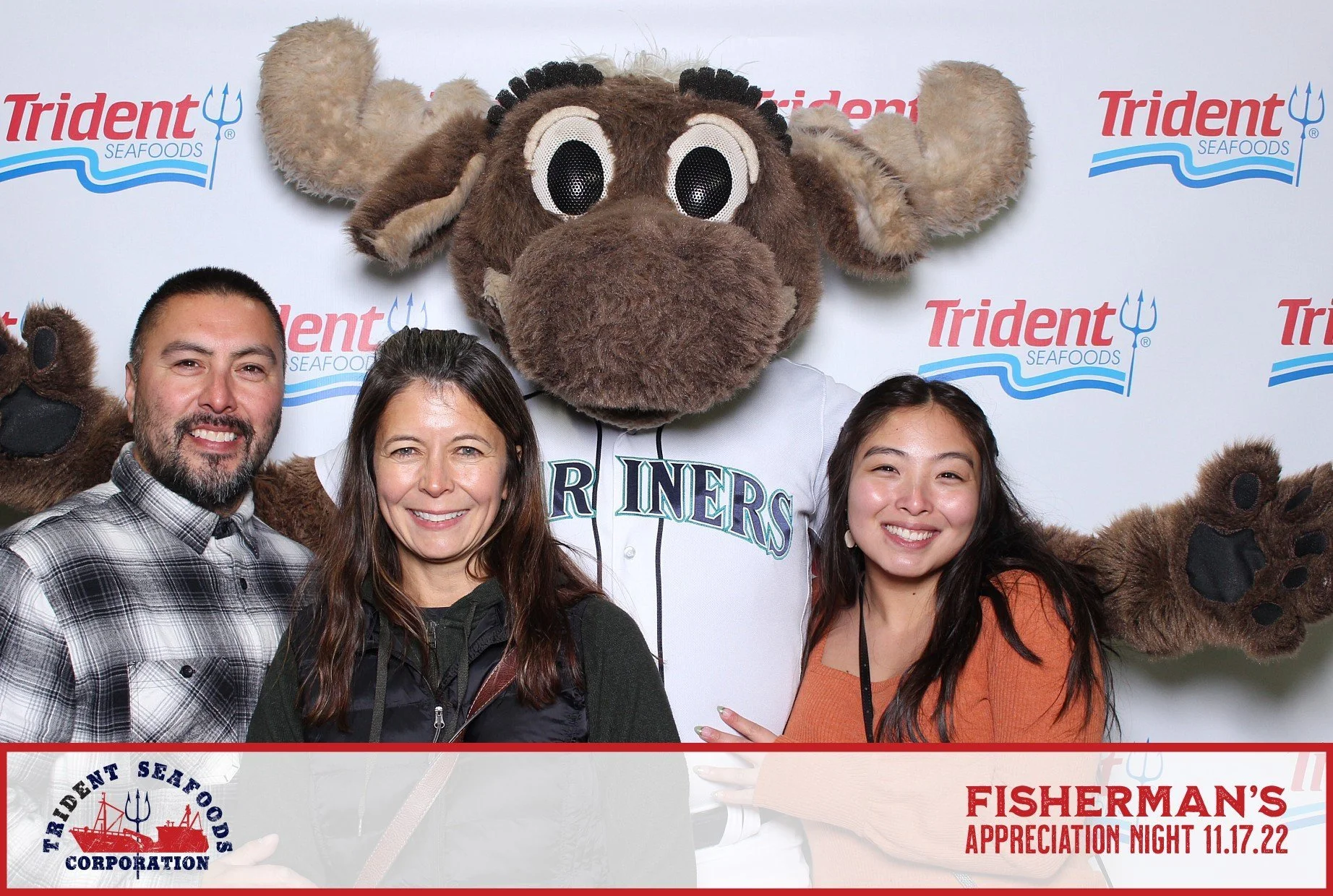 People posing with a person in a mariner mascot costume at an event with a Trident Seafoods backdrop, celebrating Fisherman's Appreciation Night, November 17, 2022.