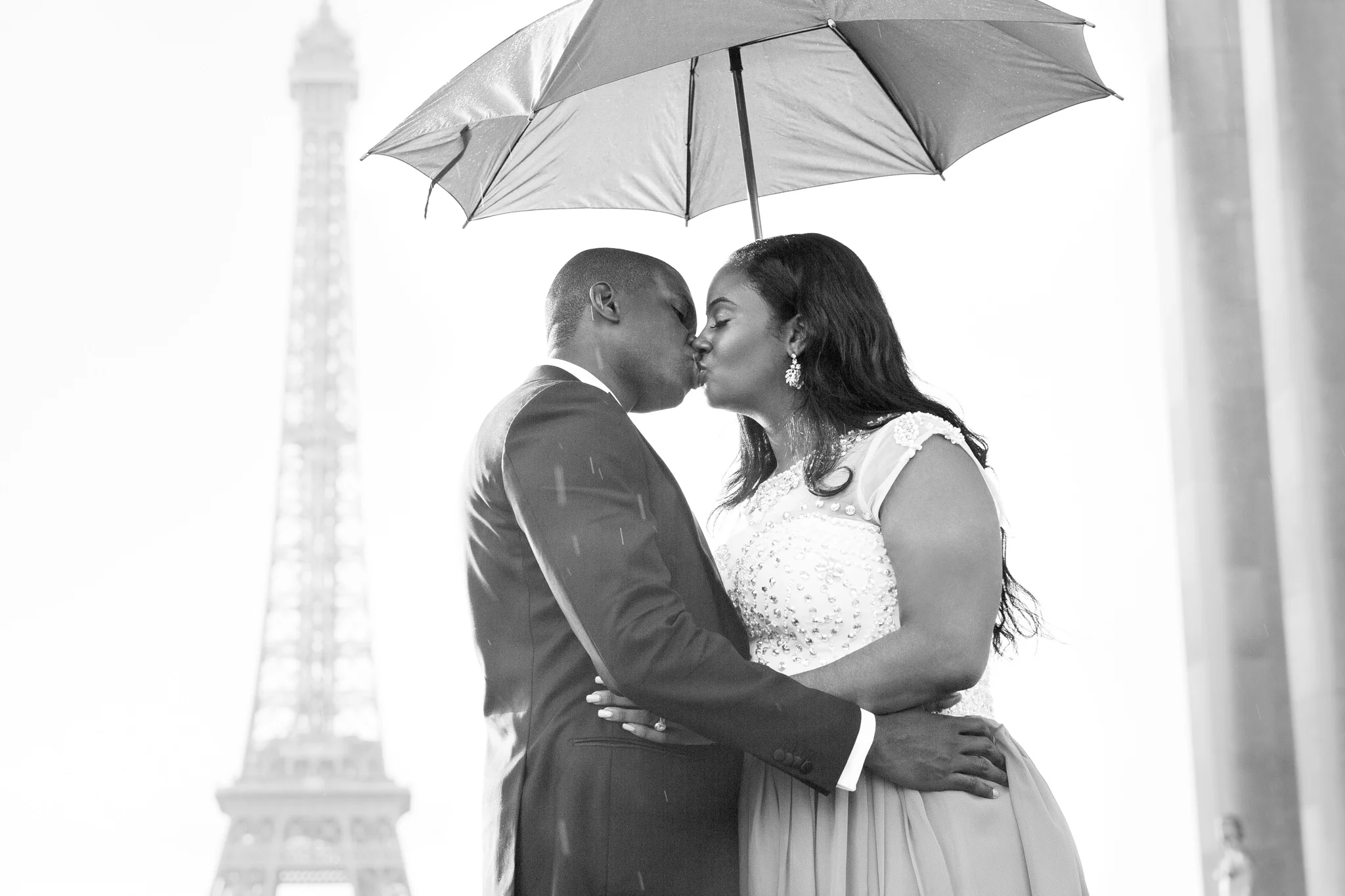 couple kissing by eiffel tower to celebrate their engagement