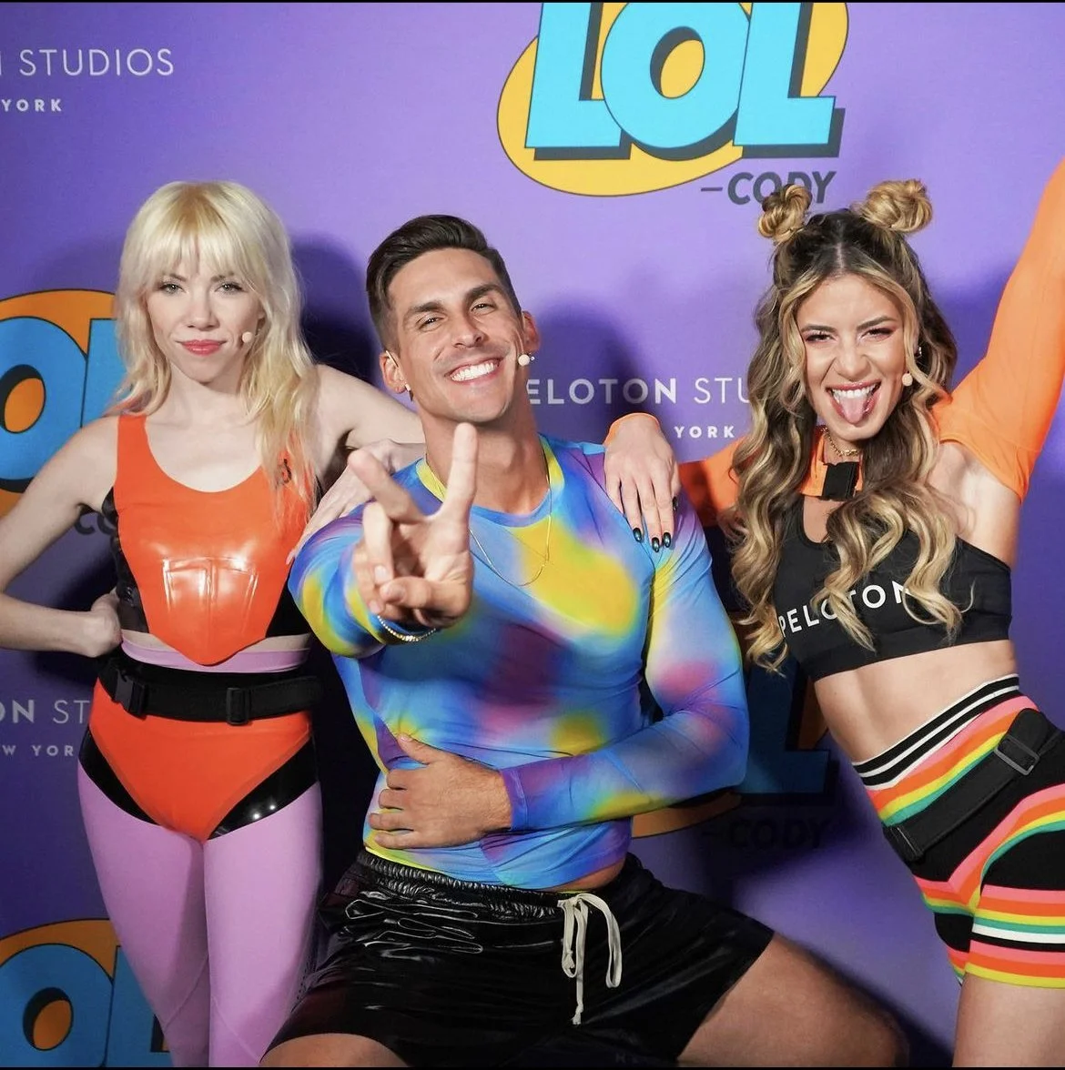  Carly Rae Jepsen wearing custom Tableaux Vivant x Peloton Latex Cycling Corset + Briefs.  Cody Rigsby wearing ASOS + Rick Owens, Kendall Toole wearing Peloton, ASOS, + Christopher John Rogers 