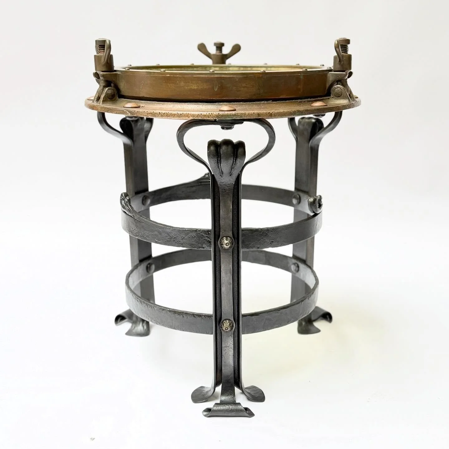 Recently completed end table commission for a themed period room in which there was an art nouveau nautical theme. Table tops from old bronze port hole ship window (with the oakum still in tact). The forged steel bases imagined naturalistic undersea 