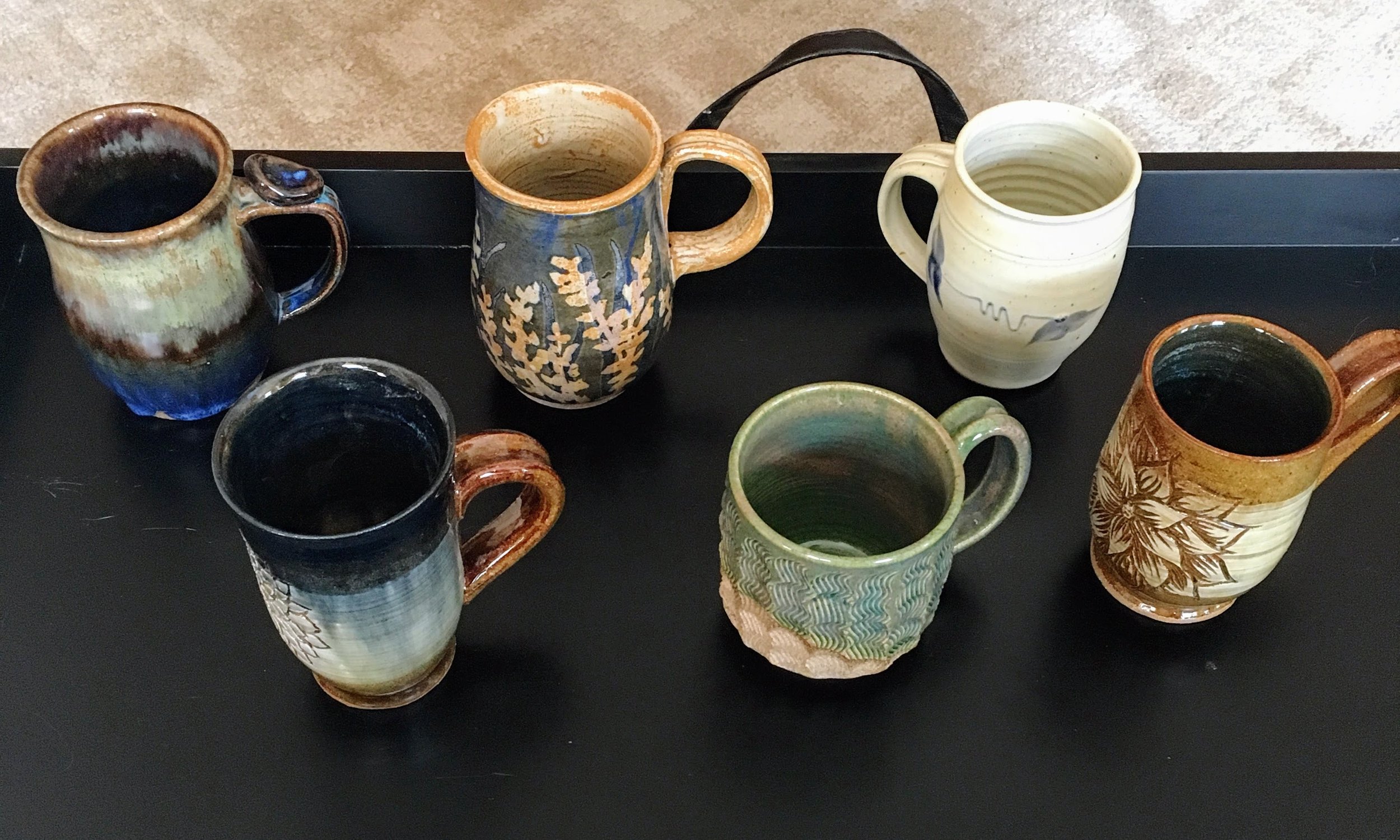 Top Row: First two are collaboration mugs made by myself, Kaila Braley , and Britt Tekla Drews and third is from Barking Spider Pottery Studio Bottom Row: Mug made by myself, middle mug was made by W ater Dragon Pottery Studio from Halifax, Nova Scotia , and the third is one of mine.