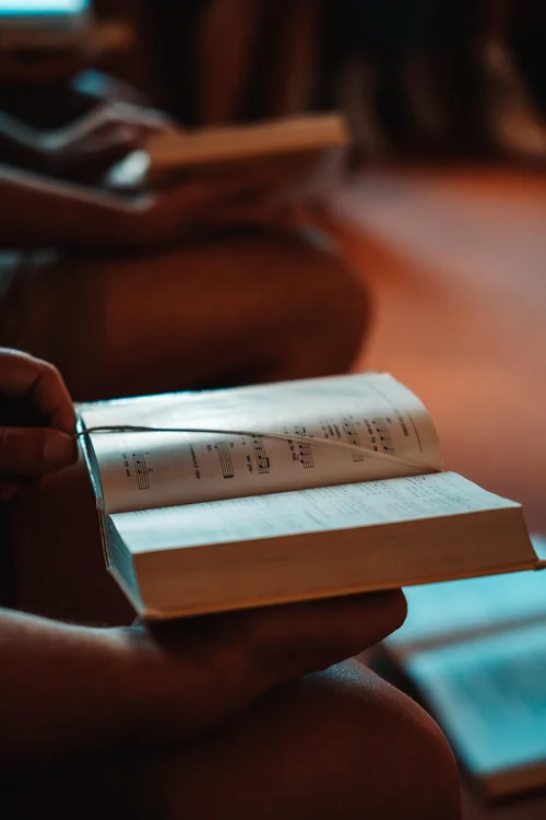 An open hymnbook held in a church pew.
