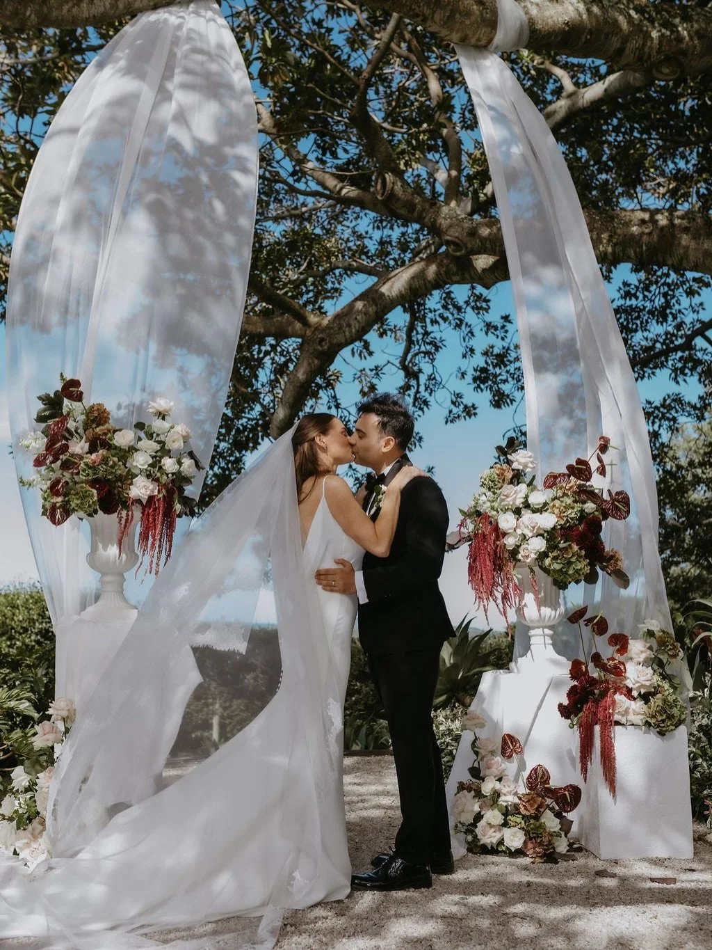 Olivia &amp; Akshaay&rsquo;s styling was all about the perfect balance of bold and breathable. They leaned into a palette of rich reds and burgundy to contrast the clean white architecture of Fig Tree Restaurant, creating a look that felt both ground
