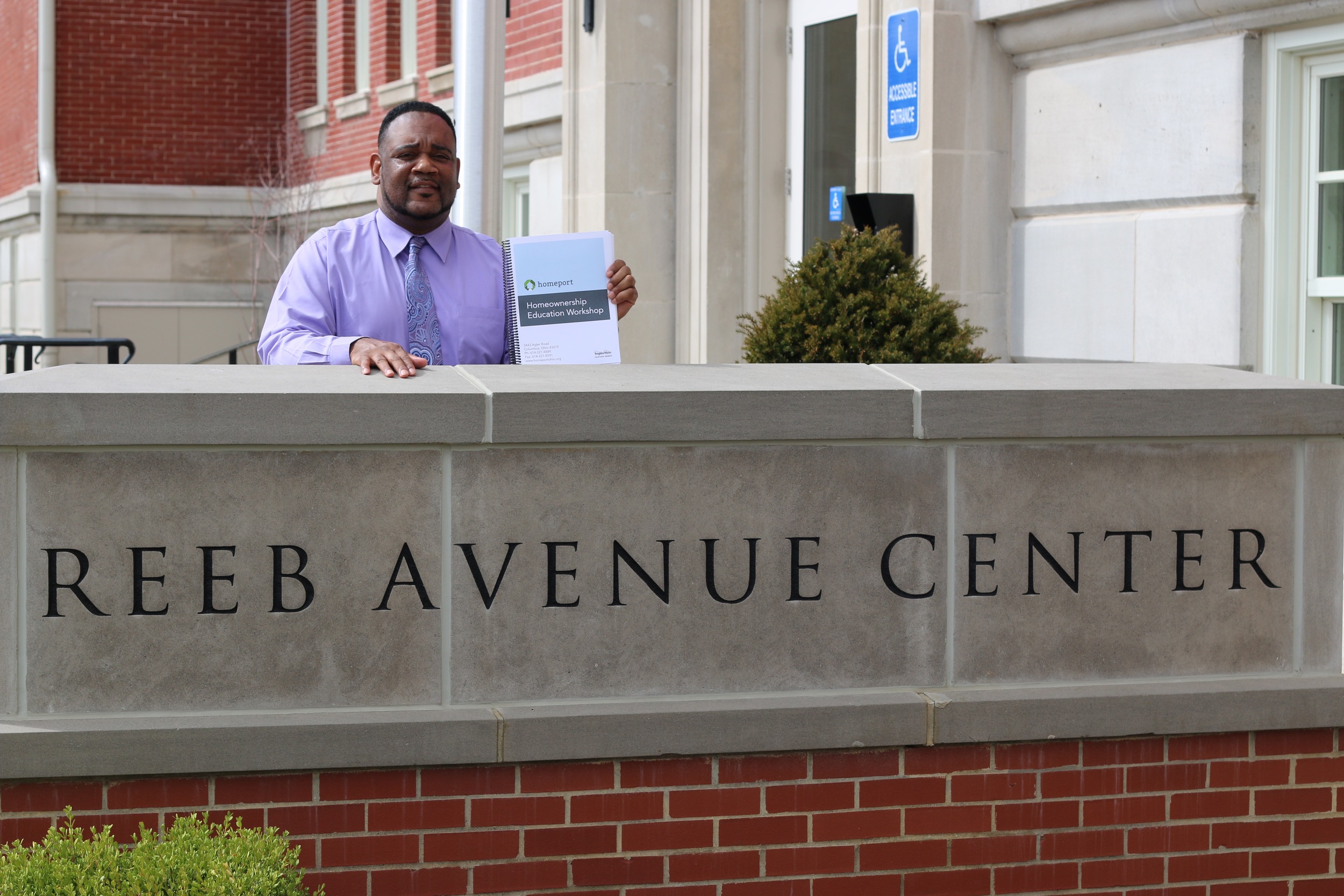 Homeport Housing Advisor Kerrick Jackson holds up book he will provide at classes