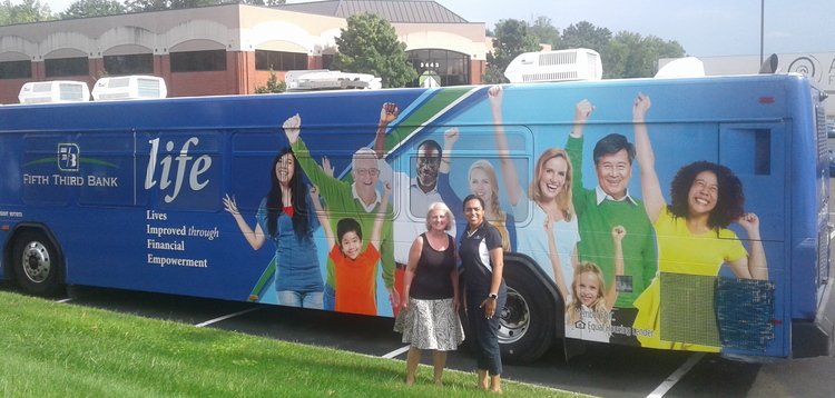 Homeport Board Chair Chris Hune, left, outside Fifth-Third Bank's 'E-Bus' last summer.