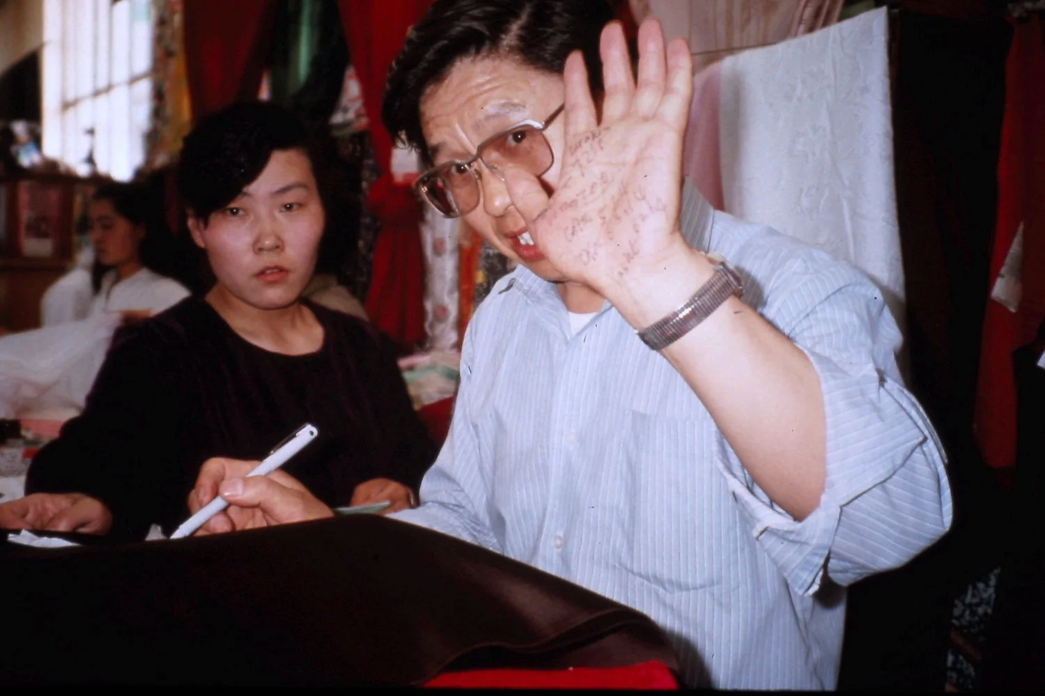Li Zhangsheng tracks our silk purchases on his hand. Lanzhou, China, May 1990. Photo: Cathy de Moll