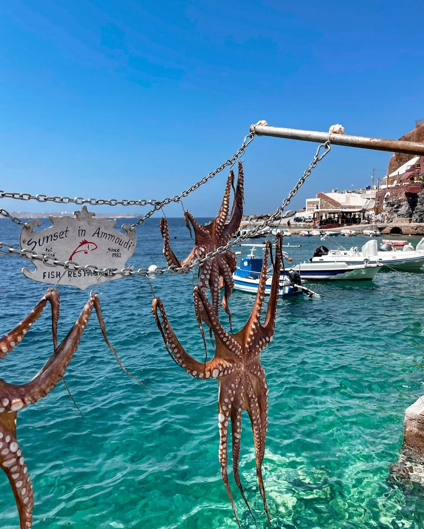 Ammo&uacute;di Bay, tucked beneath the cliffs of Oia, feels like the island&rsquo;s secret in contrast to the well-trodden paths above. 

Once a thriving fishing port, the bay, with its calm, crystal-clear waters and dramatic red-rock backdrop, is no
