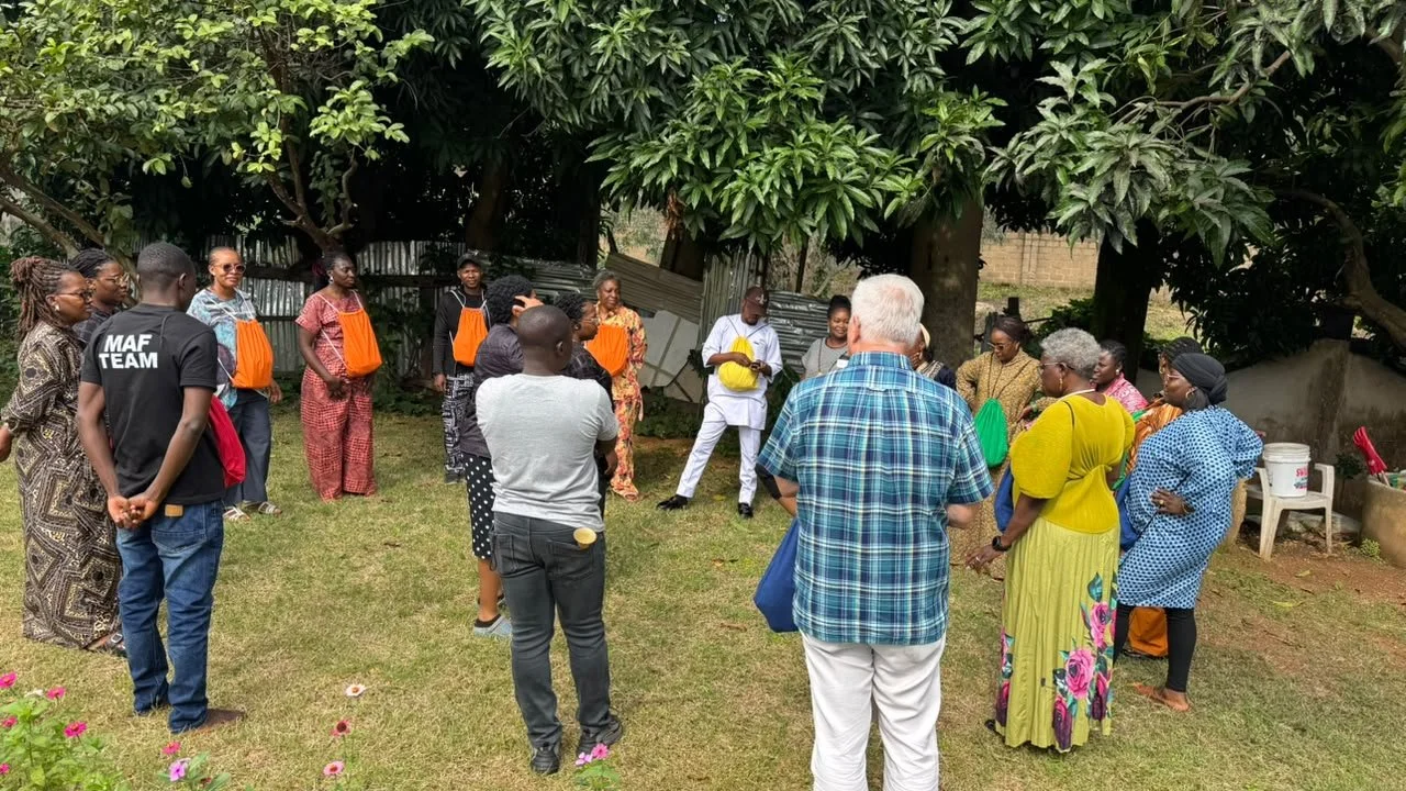 Community caregivers and Twelve12:Hope team members stand together in a circle during a Jacaranda Communities of Hope training session held outdoors