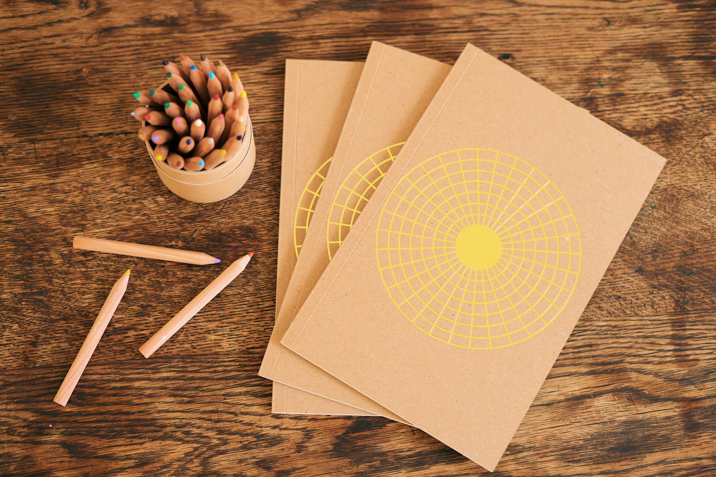 3 journals sitting on table with colored pencils, top down shot